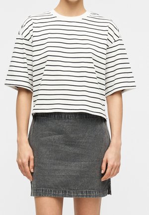 Femme portant un t-shirt blanc à manches courtes avec des rayures horizontales noires et une jupe en jean gris foncé taille haute.
