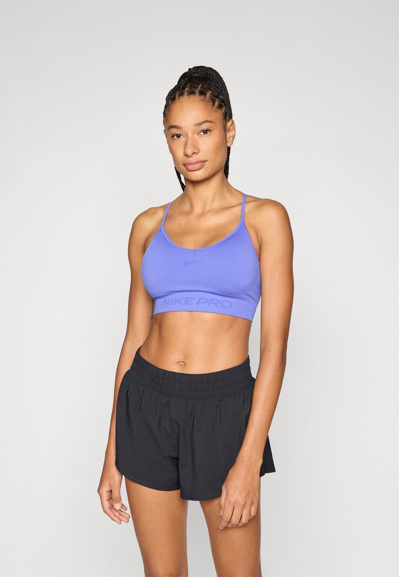 Μωβ αθλητικό σουτιέν Nike Pro με ρυθμιζόμενους ιμάντες, με το λογότυπο της μάρκας. Συνδυάζεται με μαύρο σορτς με ελαστική ζώνη μέσης.