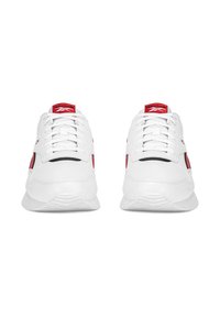 Fehér Reebok tornacipők piros logókkal, fehér fűzőkkel és fekete díszítésekkel, elölről mutatva, fehér háttéren.