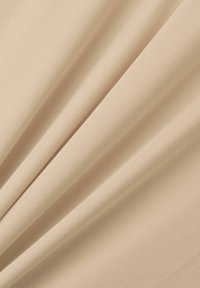 Tissu beige, lisse avec une texture douce, drapant en plis, créant un léger éclat. Matériau flexible et extensible.