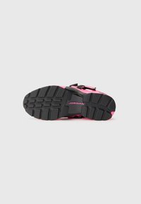 Talpa de pantof de atletism neagră și roz, cu un model de cauciuc texturat și logo-ul "JORDAN"; dispune de curele reglabile și un design conturat.