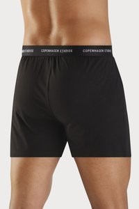 Sorte boxer shorts med blød tekstur, elastisk talje med "COPENHAGEN STUDIOS" logo, og en mellemlang længde.