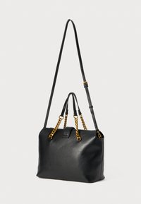 Zwarte leren handtas met een elegant ontwerp, voorzien van een afneembare schouderriem, gouden kettingaccenten en dubbele handgrepen aan de bovenkant.