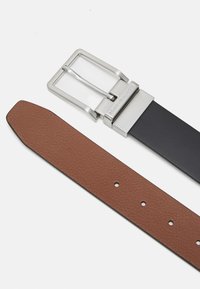 Cintura in pelle marrone con texture, dotata di una fibbia in metallo argentato e di una tracolla in pelle nera, con fori di regolazione per la vestibilità.