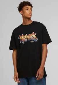 Fekete pamut póló színes "NEW YORK" grafikával, vastag betűkkel. Rövid ujjak, laza szabás és klasszikus kerek nyakú kialakítás.