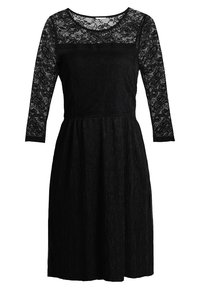 Musta mekko, jossa on pitsiset pitkät hihat ja liehuva siluetti. Yläosa sisältää läpinäkyvän pitsielementin; hameessa on teksturoitu pinta.