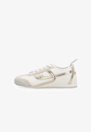 White low-top sneaker with beige accents and metallic gold curved stripe, white laces, and pull tab at heel, displayed on a white background.