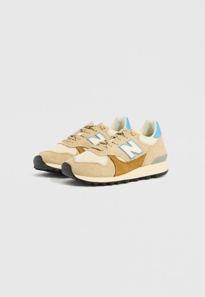 Beige und braune Wildledersneaker mit Mesh-Akzenten, blauem Logo, cremefarbigem Zwischensohlenteil und schwarzem Gummi-Außensohle. Klassisches Laufdesign mit Schnürsenkeln.
