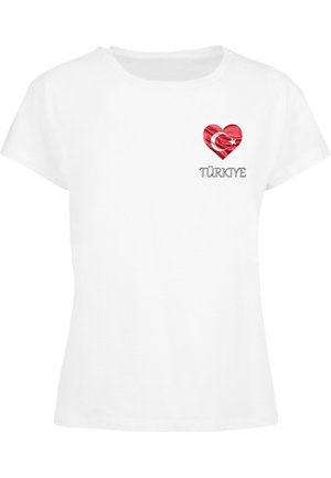 T-shirt en coton blanc avec un col rond et des manches courtes. Présente un graphisme en forme de cœur rouge avec un design de drapeau turc et le texte "TÜRKİYE".