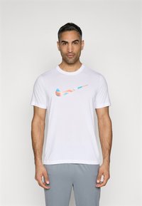 Hvit bomull T-skjorte med et flerfarget Nike-logo i blått, oransje og rosa. Kort ermer og rund hals.