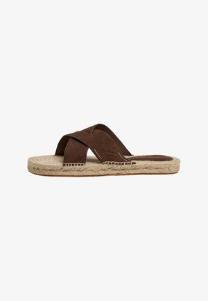 Sandalia tipo slide para hombre de ante marrón con tiras cruzadas y suela de yute tejido, mostrada de perfil sobre fondo blanco.