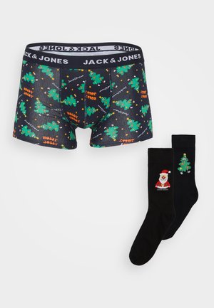 Boxer noirs avec un motif coloré de sapin de Noël et de texte, associés à des chaussettes noires arborant un design de Père Noël et de sapin de Noël.