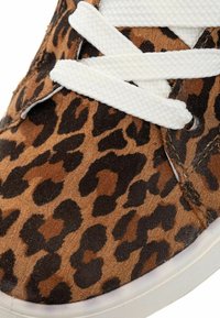 Tenisky s leopardím vzorem, které mají hnědé a černé vzory, bílé pletené tkaničky, lehký materiál a textura povrchu.