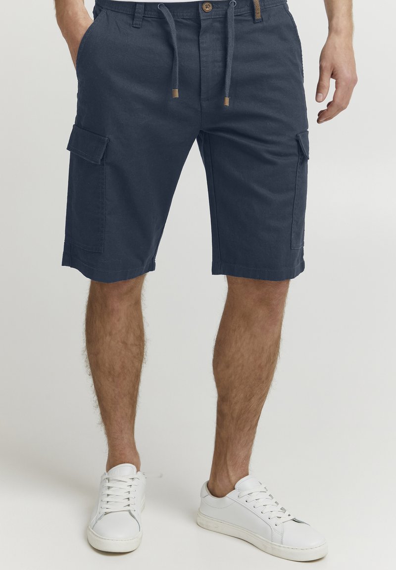 Shorts cargo bleu marine avec une ceinture à cordon de serrage ajustable, poches avant et poches cargo sur les côtés. Tissu en coton avec une finition texturée.