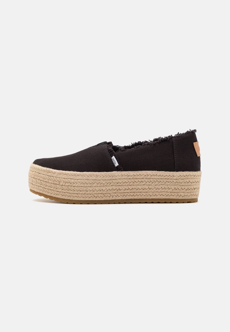 Chaussure à plateforme noire à enfiler avec semelle en corde beige tissée et bords effilochés, étiquette latérale et semelle extérieure en caoutchouc, vue de profil.