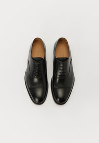 Zapatos de vestir de cuero negro con un acabado suave, diseño de puntera cerrada y cordones de seis ojales. Presentan una puntera redondeada y costuras en contraste.