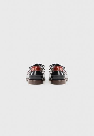 Zapatos de cuero negros y marrones con punta redonda, detalles en rojo que contrastan, cordones negros y un acabado suave. Suela de goma marrón plana.