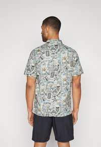 Kortermet skjorte i et lyseblått stoff med et flerfarget, geometrisk og blomsterdesign. Stilt med krage og knapppdetaljer.