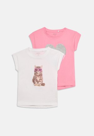 Δύο παιδικά t-shirts με κοντά μανίκια: λευκό με γατάκι που φοράει ροζ γυαλιά ηλίου σε σχήμα καρδιάς, ροζ με μεγάλη ασημένια καρδιά με γκλίτερ.