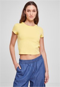 Gul kortermet t-skjorte med rund hals og glatt tekstur, sammen med l�øse bukser i denim-stil med elastisk midjebånd.