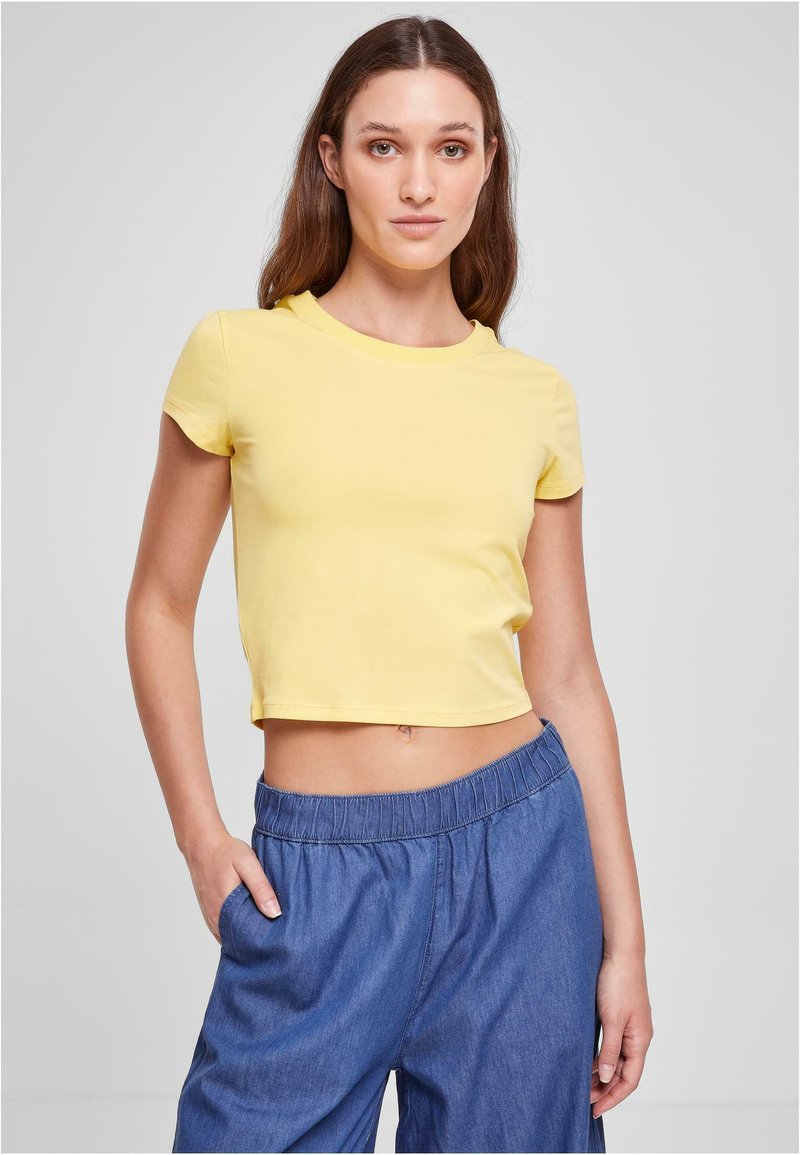 Gul cropped t-shirt med korta ärmar, rund hals och en slät textur, kombinerad med lösa byxor i denimstil med elastiskt midjeband.