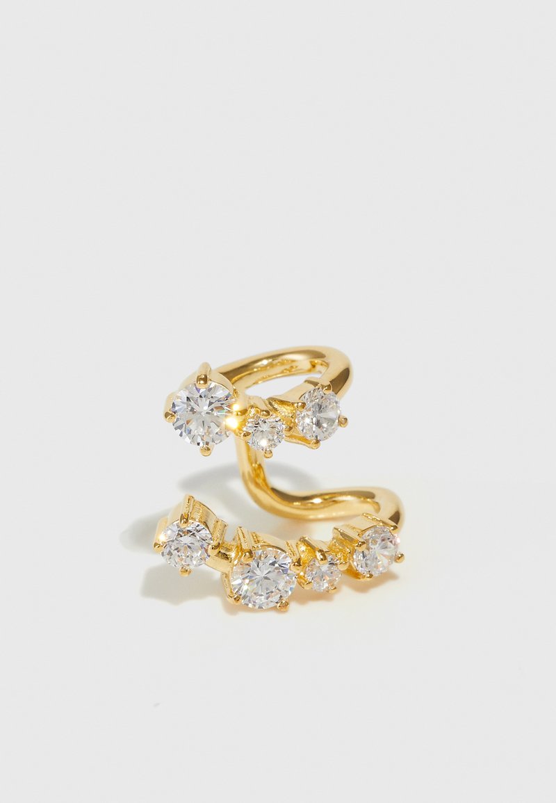 Χρυσό δαχτυλίδι που περιβάλλει τον αντίχειρα, με πολλαπλές διαυγείς πέτρες διαφορετικών μεγεθών, σε μια υφασμένη ταινία με λεία επιφάνεια.