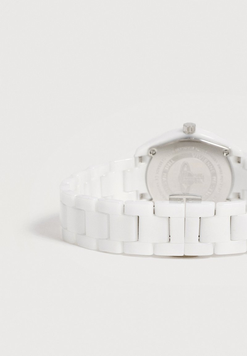 Cinturino per orologio in ceramica bianca con fibbia in metallo, mostrato da dietro con parte della cassa dell'orologio visibile su sfondo bianco.