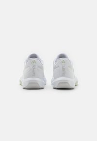 White athletic shoes with a textured mesh upper, featuring a green accent on the heel and the word "TRAINING" embossed on the side.