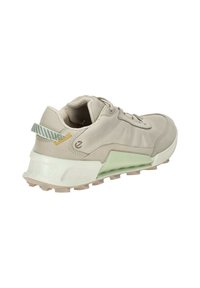 Beige athletic shoe with mesh and synthetic materials, featuring a chunky white and mint green sole, textured accents, and a pull tab.