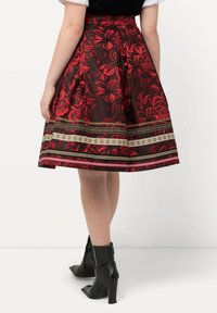 Een zwart en rode rok met bloemenpatroon en een uitlopende stijl, voorzien van ingewikkelde randen en een gestructureerde satijnachtige afwerking.