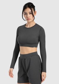 Cropped top sportivo grigio scuro con maniche lunghe, design senza cuciture e scollatura rotonda, abbinato a pantaloni corti a vita alta coordinati.