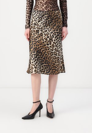 Jupe midi imprimée léopard en tissu satiné, avec une taille cintrée et un ourlet évasé, associée à des chaussures à talons hauts noires.