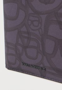 Paarse gestoffeerde portemonnee met een lijntekeningpatroon van brillen. Voorzien van een geperst "KARL LAGERFELD"-logo in zwart. Gladde afwerking, slank ontwerp.