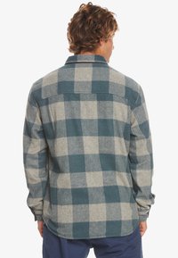 Geruite flanellen shirt in blauw- en grijstinten, met een knoopsluiting, lange mouwen en een ronde onderkant. Zachte textuur met een schots patroon.