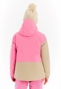 Farbig blockierte Jacke mit einem rosa oberen Abschnitt und einem beigen unteren Abschnitt, mit Kapuze und elastischen Bündchen. Strukturiertes gestricktes Mütze auf dem Kopf.