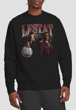 Man wearing black sweatshirt with three illustrations of a long-haired man in different outfits and the text "LESTAT" above them.