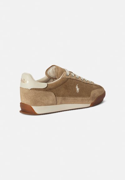 Καφέ σουέντ αθλητικό παπούτσι με μπεζ δερμάτινες λεπτομέρειες, διαθέτει λευκό λογότυπο, στρογγυλή μύτη και ελαστική σόλα με ανάγλυφη επιφάνεια και ελαφρύ τακούνι.