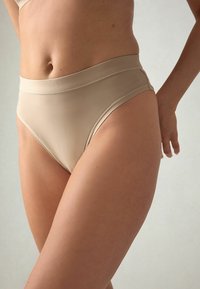 Gole nude visoke gaćice bez šavova izrađene od glatkog, rastezljivog materijala. Imaju mekani pojas i minimalne šavove za udobnost.
