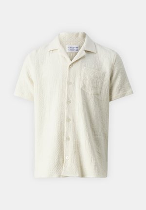 Lühikeste varrukatega nööbid üles särk tekstureeritud kreemjas kangas, rinna taskuga. Omab klassikalist kraed ja peent, heledat mustrit.