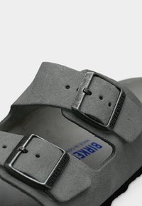 Γκρι σανδάλια Birkenstock με δύο ρυθμιζόμενες λουρίδες, με ασημένιες μεταλλικές αγκράφες. Μαλακή σουέτ υφή και σχεδιασμός με ανατομικό πέλμα.