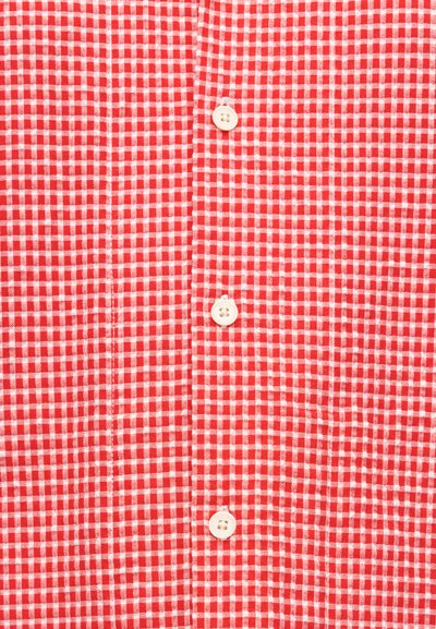 Πουκάμισο κόκκινο και άσπρο καρό με τέσσερα λευκά κουμπιά τοποθετημένα κάθετα στη μέση μπροστά.