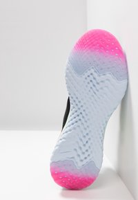 Černá atletická podešev s vlnitým vzorem. Gradient od růžové po bílou blízko paty a texturovaná kruhovými vzory pro lepší trakci.