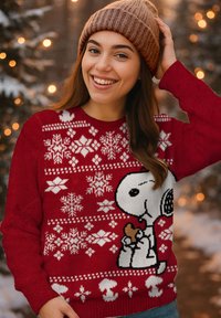 Maglione rosso lavorato a maglia con motivi a fiocchi di neve bianchi e un design di Snoopy che tiene un piccolo cane. Collo ed estremità a coste.
