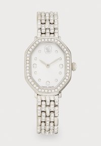 Silberne achteckige Uhr mit einem weißen Zifferblatt, umgeben von einem mit Kristallen besetzten Gehäuse und einem strukturierten, mehrreihigen Armband. Schweizer Herstellung.