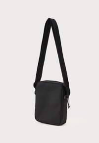 Borsa a tracolla nera di forma rettangolare, realizzata in materiale liscio. Presenta una tracolla piatta e una chiusura a zip. Design semplice, senza motivi visibili.