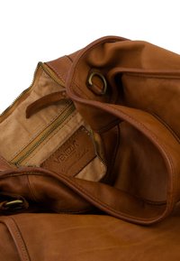 Brun læderhåndtaske med en glat tekstur, der har en indvendig lynlåslomme og et logo med teksten "Ægte Læder".