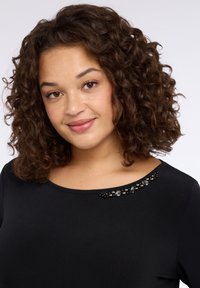 Czarny top z okrągłym dekoltem, zdobiony czarnymi i szarymi kryształkami wzdłuż szwu na ramieniu. Miękka, gładka faktura materiału.