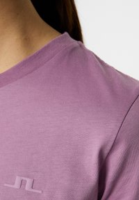 Lilla t-shirt med korte ærmer lavet af blød bomuld, med en rund halsudskæring og et diskret præget logo på brystet.