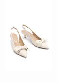 Beige-slingback-kengät, joissa on terävä kärki, edessä leveä nauhaliitos ja matala kitten-korko. Tasainen nahkapinta.