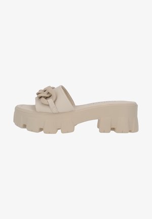 Sandales à plateforme beiges avec une semelle épaisse et texturée et un détail de sangle nouée. Matériau lisse avec un design minimaliste.